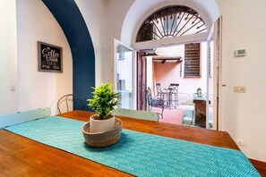 A dining area with a wooden table, a potted plant, and a blue patterned table runner.