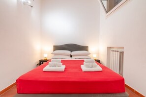 A hotel room with a large bed, two bedside tables, a nightstand, and a radiator.
