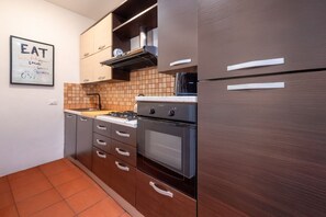 A modern kitchen with wooden cabinets, a gas stove, an oven, and a stainless steel refrigerator.