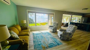 A living room with a sofa, two patterned armchairs, a coffee table, and a view of a balcony with a railing.