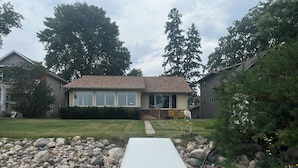 A house with a front yard, a pathway leading to the front door, and a small deck area.