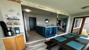 A kitchen with a coffee station, a blue cabinet, and a dining area with a table.