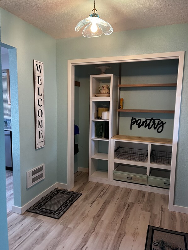A room with a 'WELCOME' sign, a 'pantry' sign, and a wooden floor. - Charming 3-bedroom lake front house with WiFi, AC on marvelous West Battle Lake (Battle Lake)