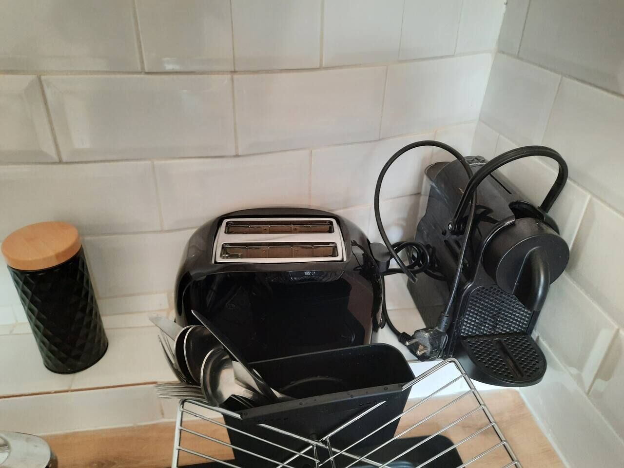 Een keuken met een broodrooster, een koffiezetapparaat en een afvalbak.