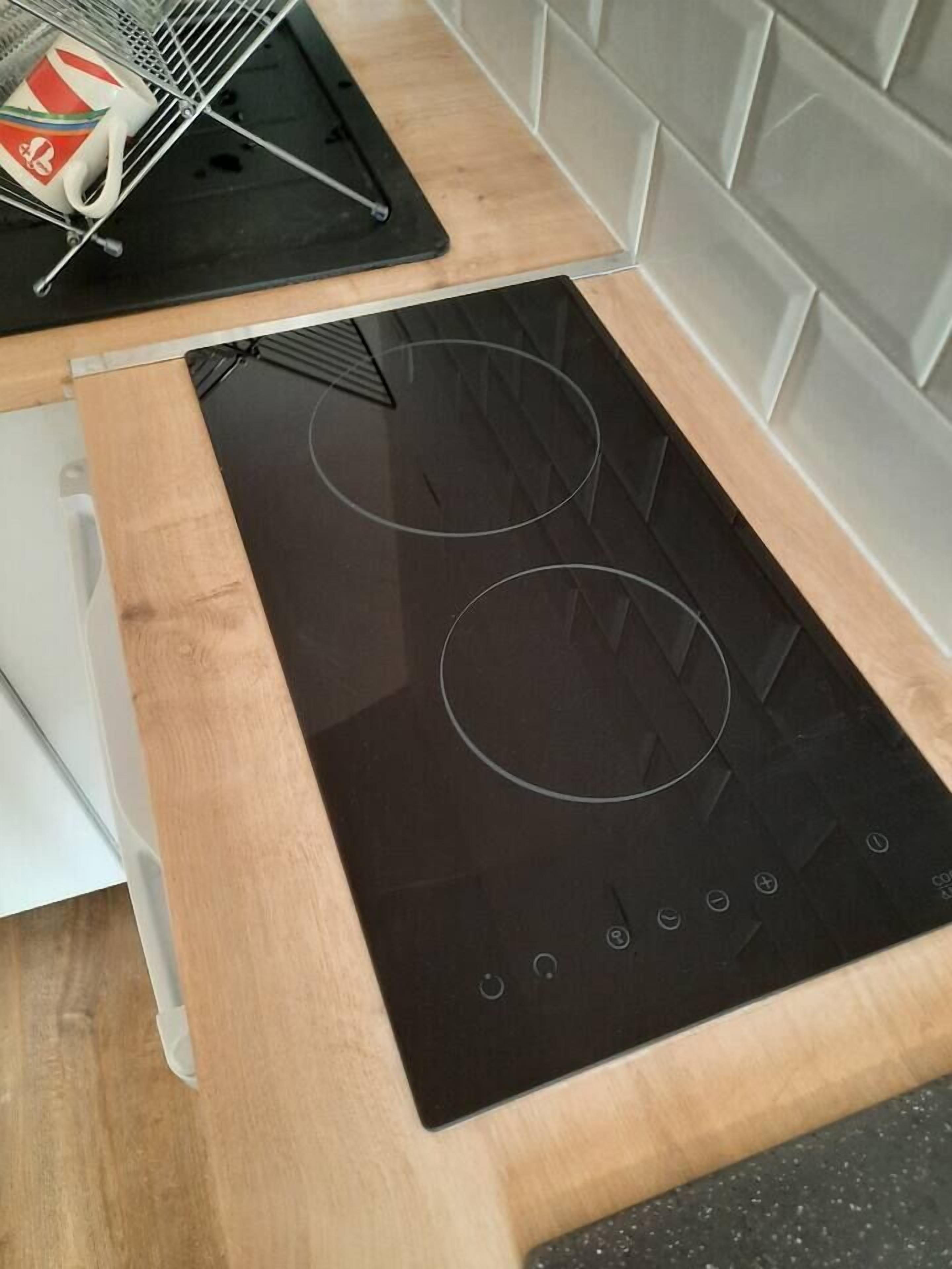 A modern kitchen with a black induction cooktop and a wooden countertop.