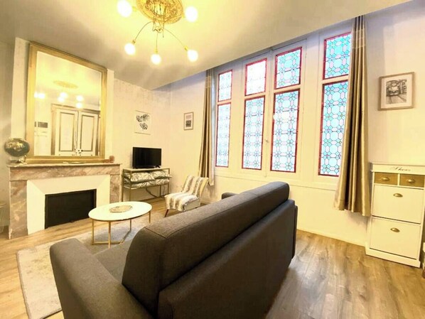 A living room with a fireplace, a sofa, a television, and a dining table.