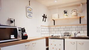 Una cocina compacta con gabinetes blancos, un microondas, un refrigerador y una pequeña encimera.