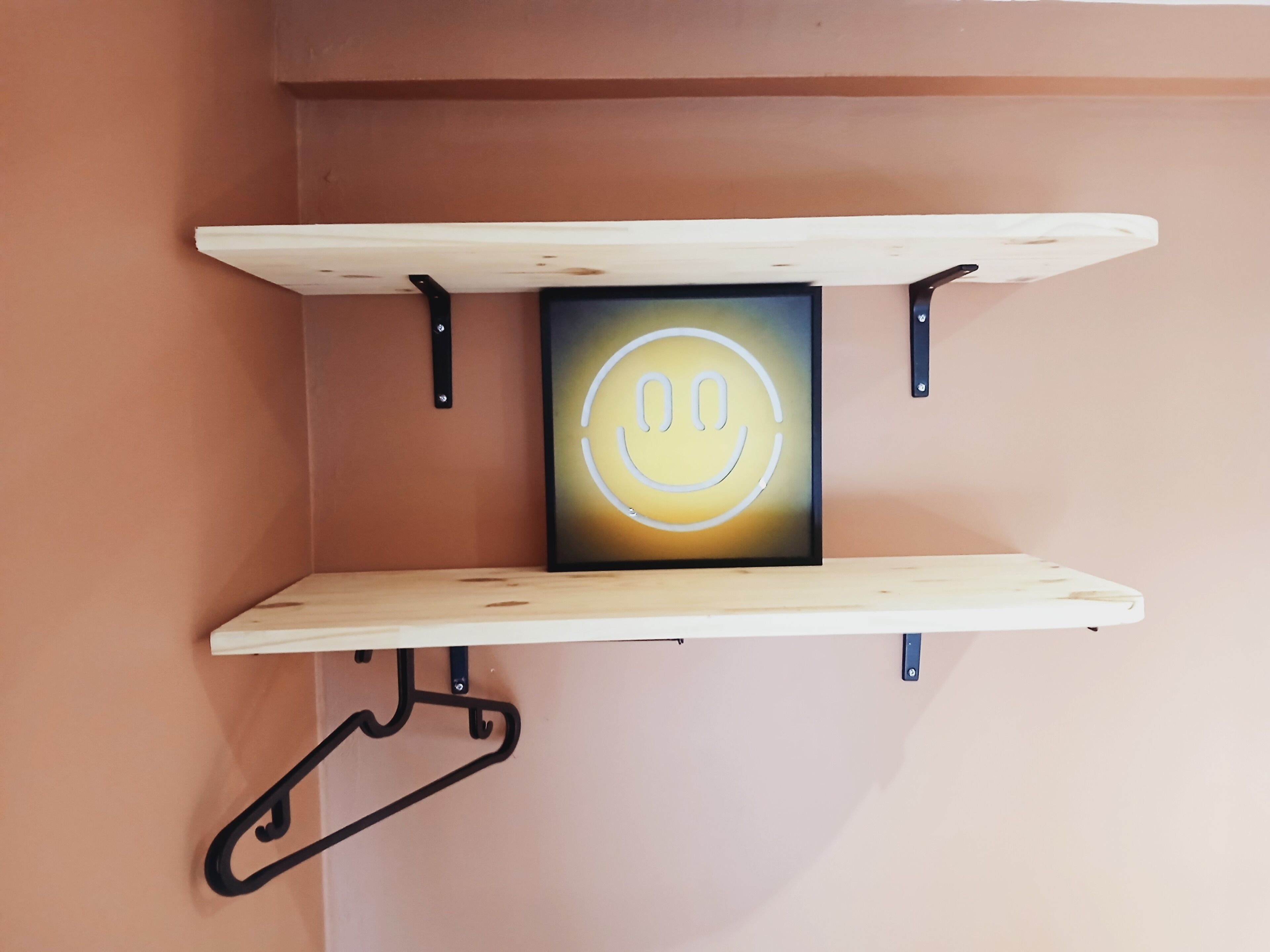 A wall-mounted shelf with a smiley face decoration.
