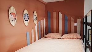 Un dormitorio con una cama, almohadones de lunares y tres tablas de surf en la pared.