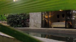 A modern bedroom with a glass door, a bed, and a view of the surrounding greenery. - New years special! Your private jungle escape! (Quepos)