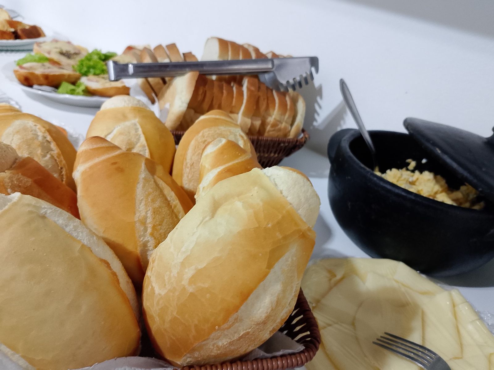 Una mesa con varios tipos de pan y un bol de huevos revueltos.