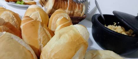 A table with various types of bread and a bowl of scrambled eggs.