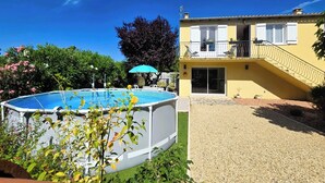 A residential property with a swimming pool, a covered patio, and a two-story building with a balcony.