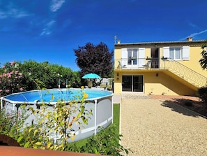 A residential property with a swimming pool, a covered patio, and a two-story building with a balcony.