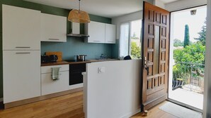 A modern kitchen with white cabinets, a wooden countertop, and a hanging light fixture.
