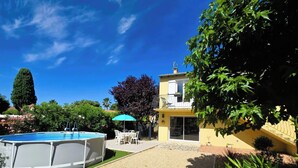 A residential property with a swimming pool, outdoor seating, and a two-story building.