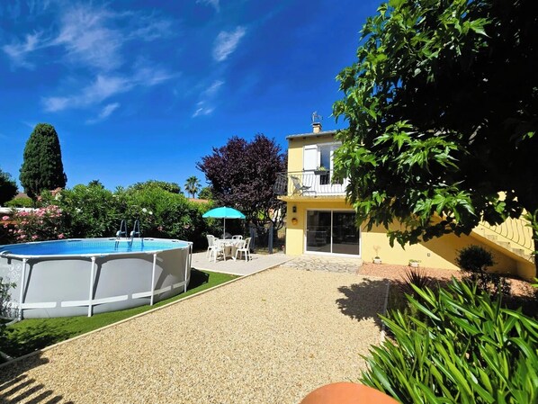 A residential property with a swimming pool, outdoor seating, and a two-story building.