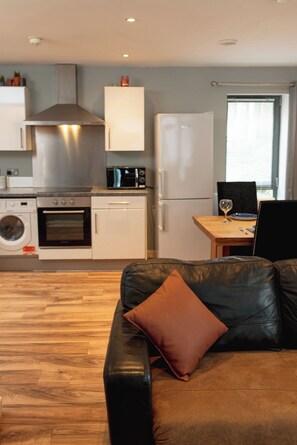 Una cocina moderna con estufa, horno, microondas y refrigerador. Cuenta con un comedor con mesa y sillas.