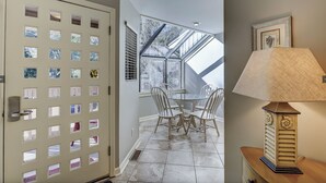 Ein Zimmer mit Esstisch und Stühlen, einer Lampe und einer Tür mit mehreren Fenstern.