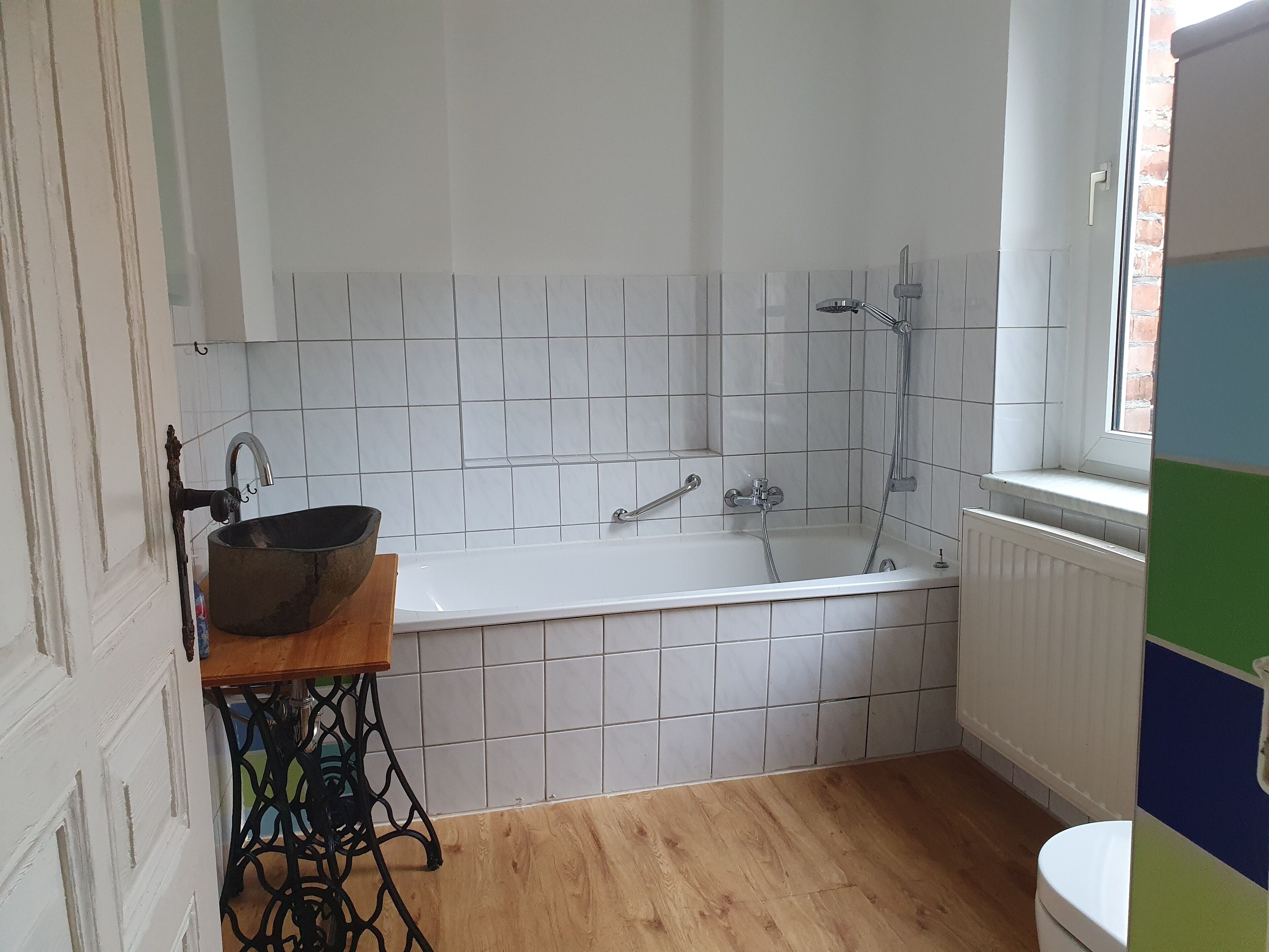 Un baño con una bañera blanca, un lavamanos y una ventana.