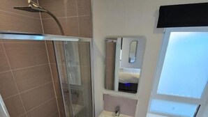 Une salle de bain moderne avec une douche à parois de verre, un lavabo avec un miroir au-dessus et des toilettes.