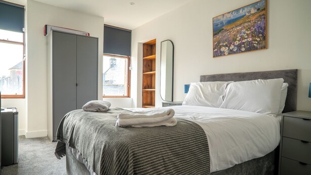 Une chambre à coucher comprenant un lit, une armoire, une table de chevet, un miroir et un tableau accroché au mur.