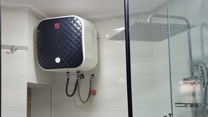 A modern bathroom with a glass shower enclosure, a built-in heater, and a small storage cabinet. - Super Deluxe Room #1 (Ikeja)