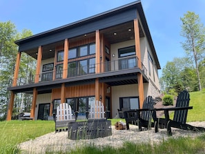 Un immeuble à plusieurs étages doté d’un balcon, d’un espace extérieur am énagé pour s’asseoir et d’une zone recouverte de gravier.