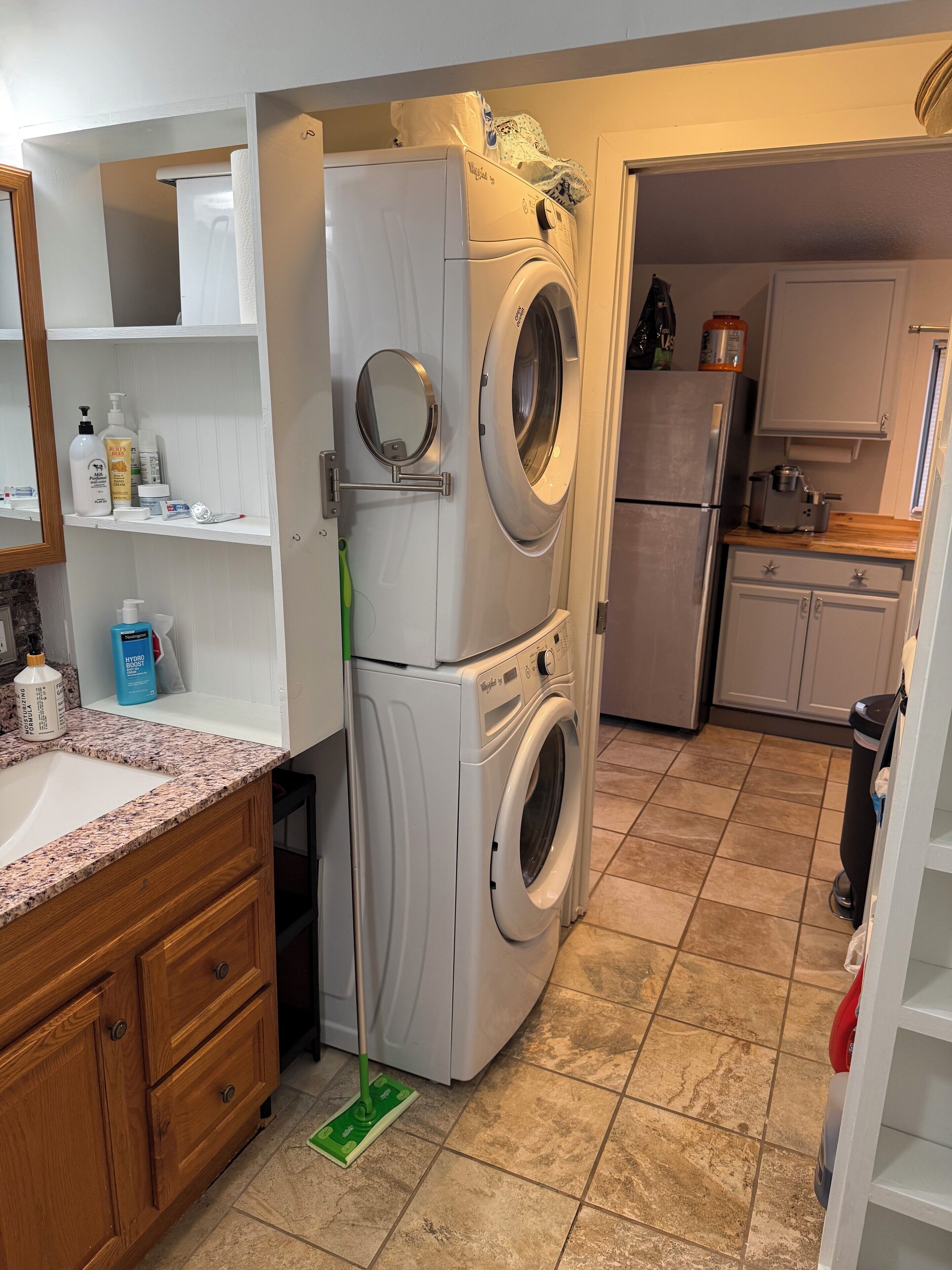 A compact kitchen with a built-in washer and dryer, a wooden cabinet, and a tiled floor.