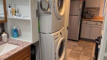 A compact kitchen with a built-in washer and dryer, a wooden cabinet, and a tiled floor.