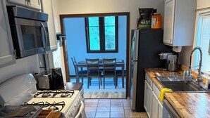 A kitchen with a stove, microwave, and sink, leading to a dining area with a table and chairs.