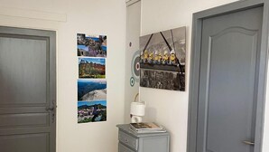 Un passadís amb una porta i un armari de color gris, i un quadre amb un paisatge urbà penjat a la paret.