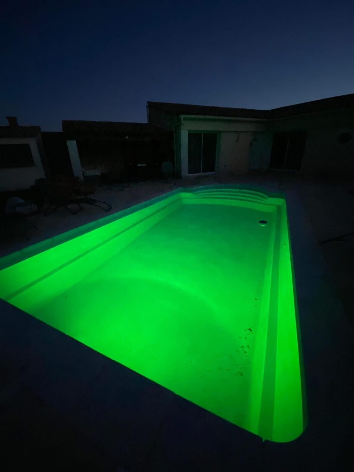 Une piscine rectangulaire éclairée d’une lumière verte.