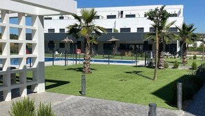 A modern building with a pool, palm trees, and a well-maintained lawn. - Newbuild apartment Estepona pool - beach - gym (Estepona)