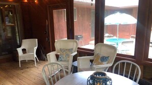 A cozy room with wicker furniture, a round table with a lantern, and large windows with an umbrella. - The Best of Both Worlds – 3 bedroom house with Lake Access Without the Crowds (Mears)