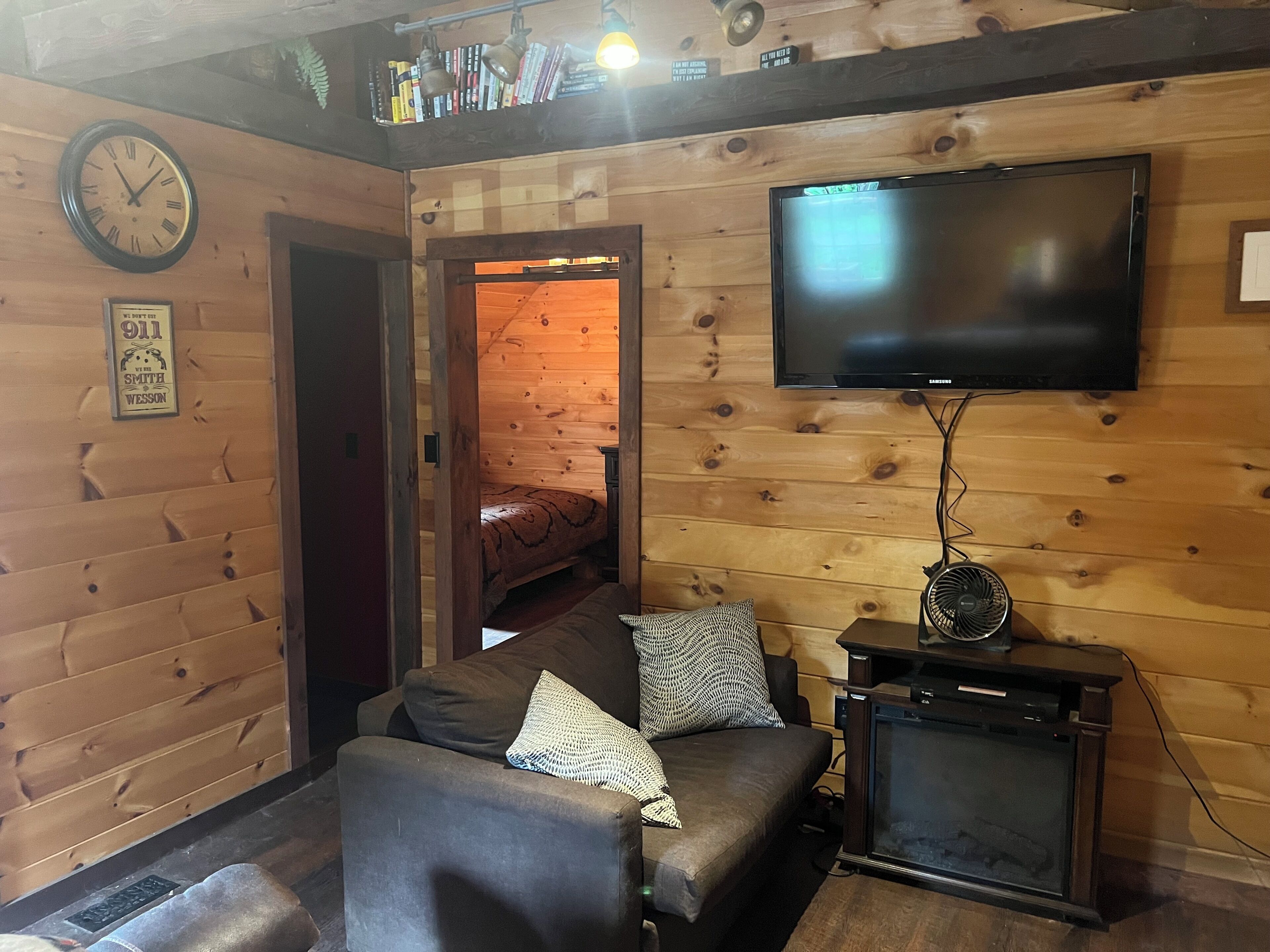 Un salon chaleureux avec un canapé, un téléviseur à écran plat fixé au mur et un plafond en bois.