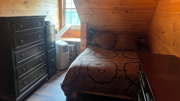 A small, cozy room with a bed, a dresser, and a window. - Charming cabin in wonderful New Sweden with 80 acres of woods and trails (New Sweden)