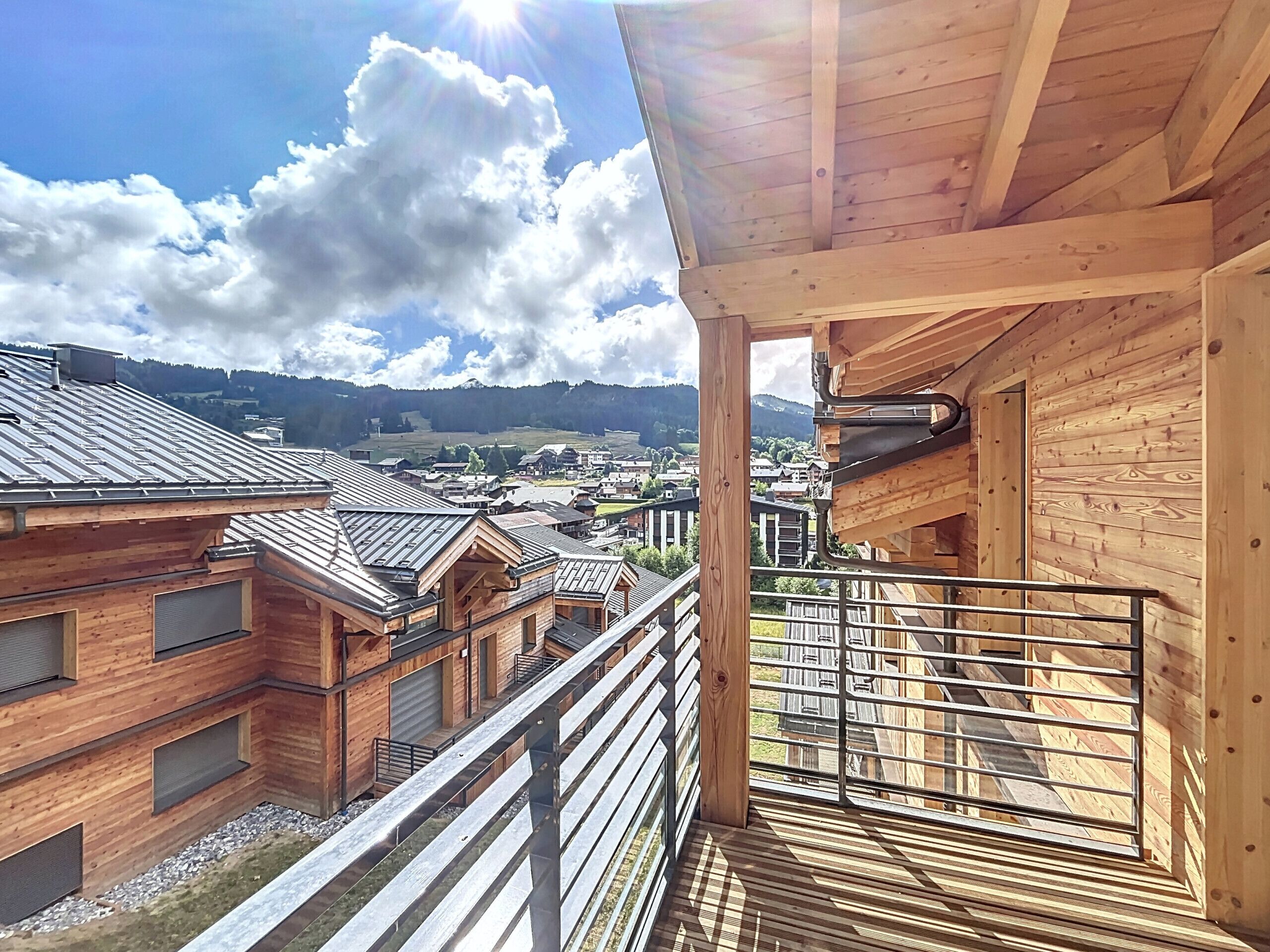 Une cabane en bois dotée d’un balcon donnant sur un village et des montagnes.