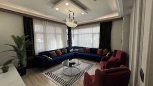 Ein modernes Wohnzimmer mit einem blauen modularen Sofa, einem runden Couchtisch und roten Sessel.
