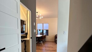 Un pasillo con comedor, suelo de madera y una escalera.