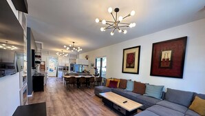 Una sala de estar moderna con un sofá seccional gris, una mesa de centro de madera y un comedor con una isla central.