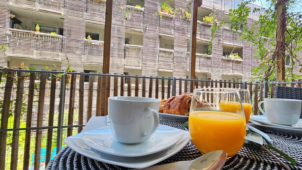 An outdoor dining area with a table set for breakfast, including croissants and orange juice. - Cosy Apartment In A Green Setting -Nice (Nice)