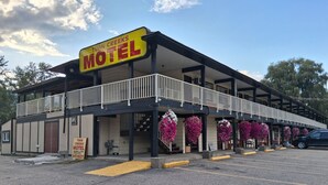 A motel with a balcony, a signboard, and hanging flower baskets. - Twin Creeks Motel (Lumby)