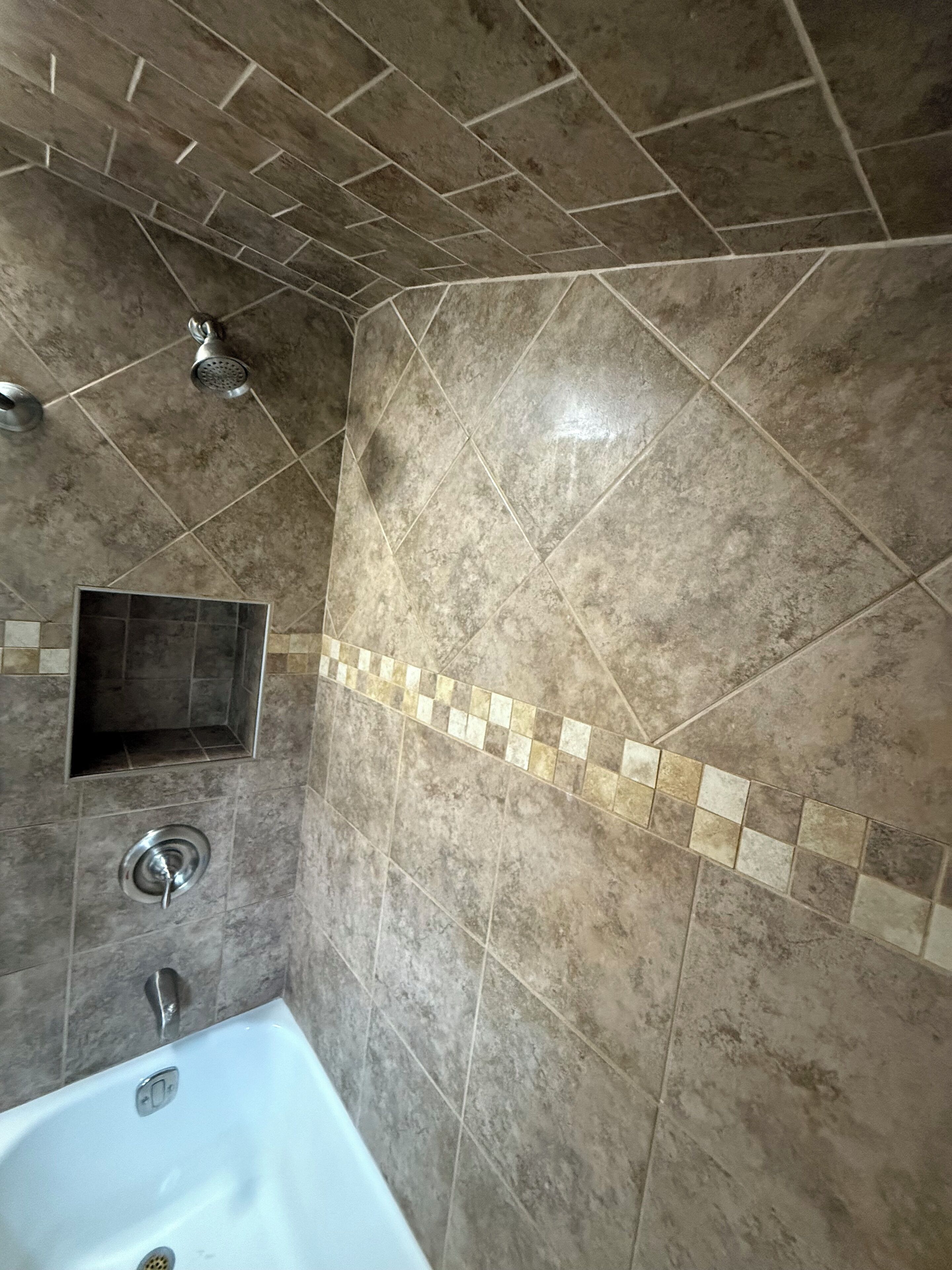 A bathroom with a bathtub, a shower, and a tiled wall.