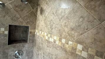 A bathroom with a bathtub, a shower, and a tiled wall.