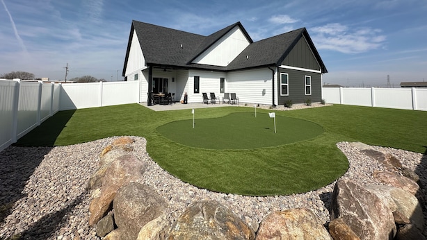 A house with a covered patio, a lawn, and a rock border.
