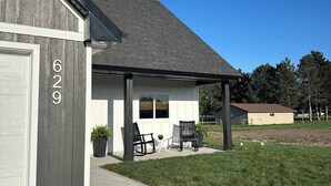 A single-story building with a garage door, a covered porch with chairs and a table, and a number '629' on the side.