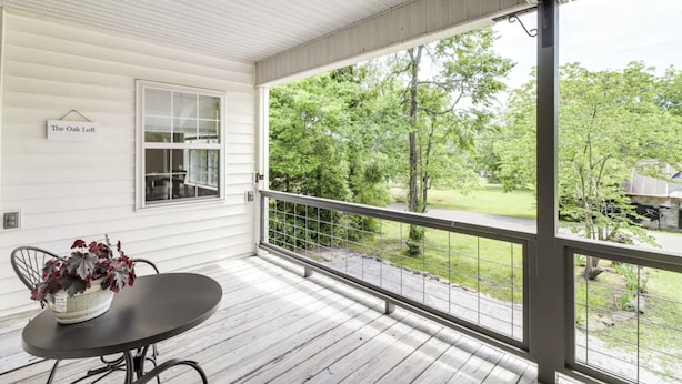 A covered porch with a table and chairs, a window, and a view of a green landscape. - Minutes to the Square • Fire Pit • Dog Friendly (Mountain View)