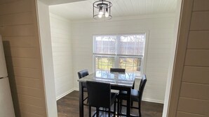 A dining area with a table and chairs, a window with blinds, and a ceiling light fixture. - Minutes to the Square • Fire Pit • Dog Friendly (Mountain View)