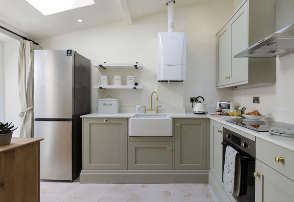 A modern kitchen with a built-in refrigerator, a sink, and a stove. There are cabinets and a countertop with various kitchen items.